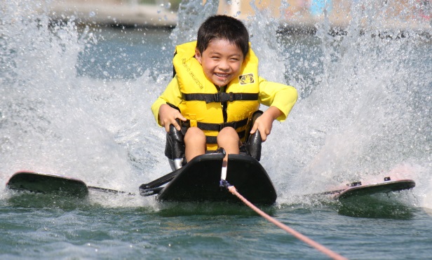 a boy uses an assistive device to water ski