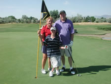 Mother, father, and son standing on a golf course.